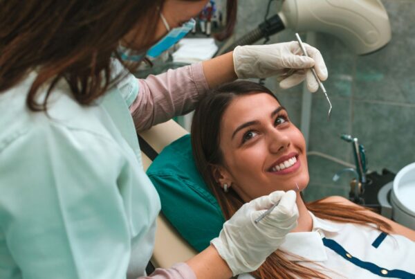 Woman smiling in the dental chair deciding between caps or veneers